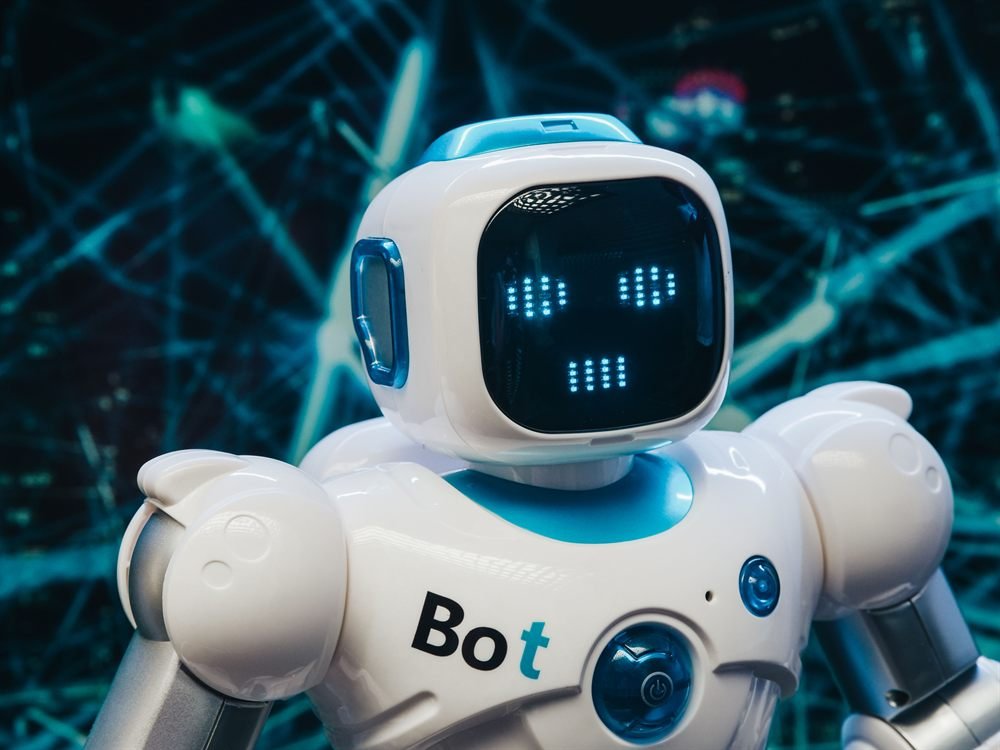A small white and blue robot with a pixel-lit smiling face