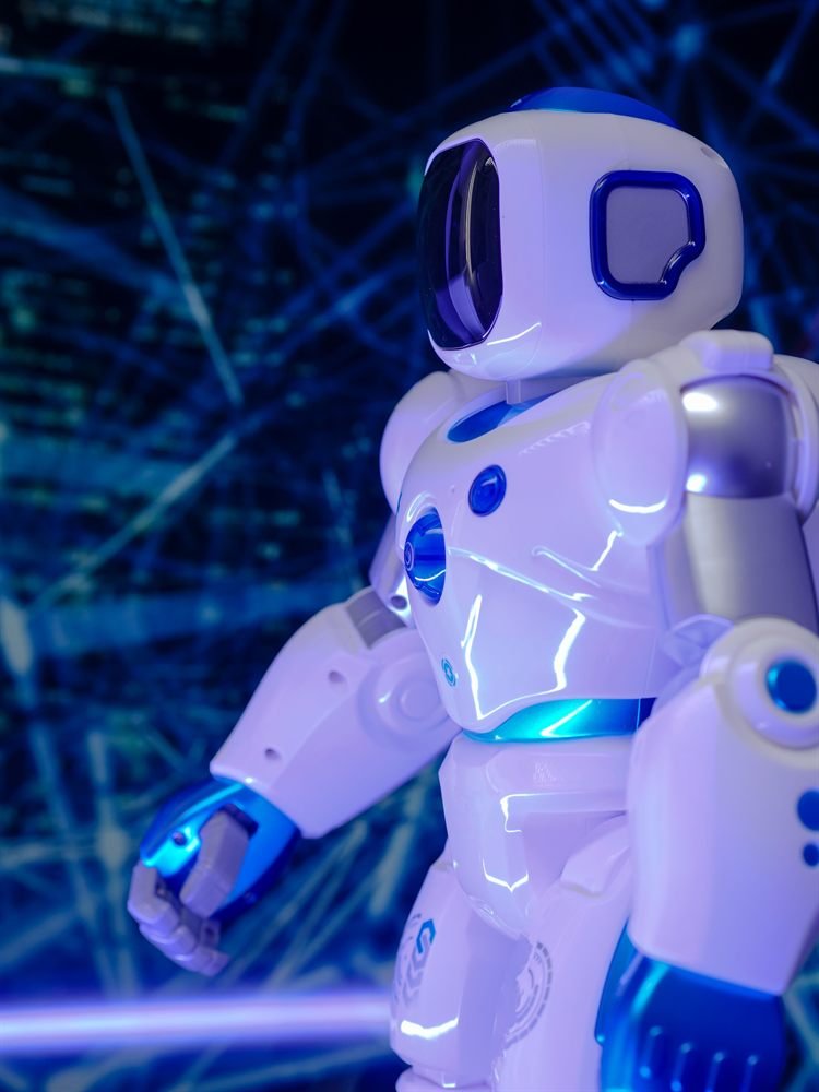 A toy robot in profile, lit blue, reaching forward
