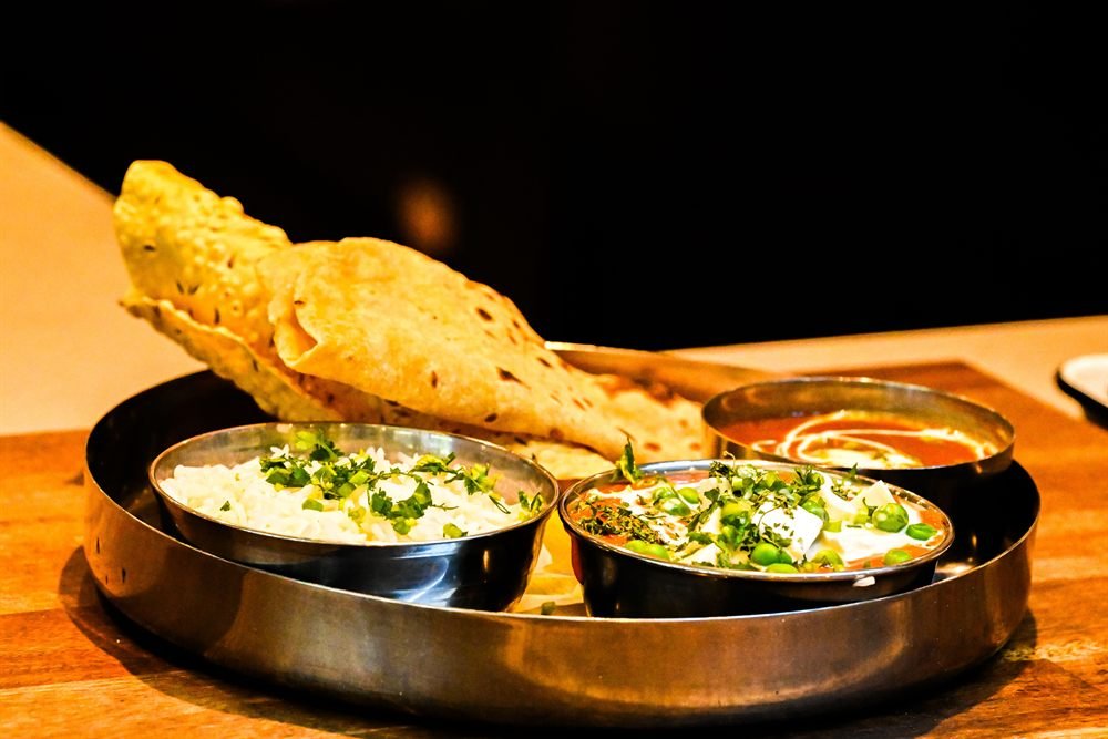 An Indian thali of rice, paneer curry and dal with a crisp papadum