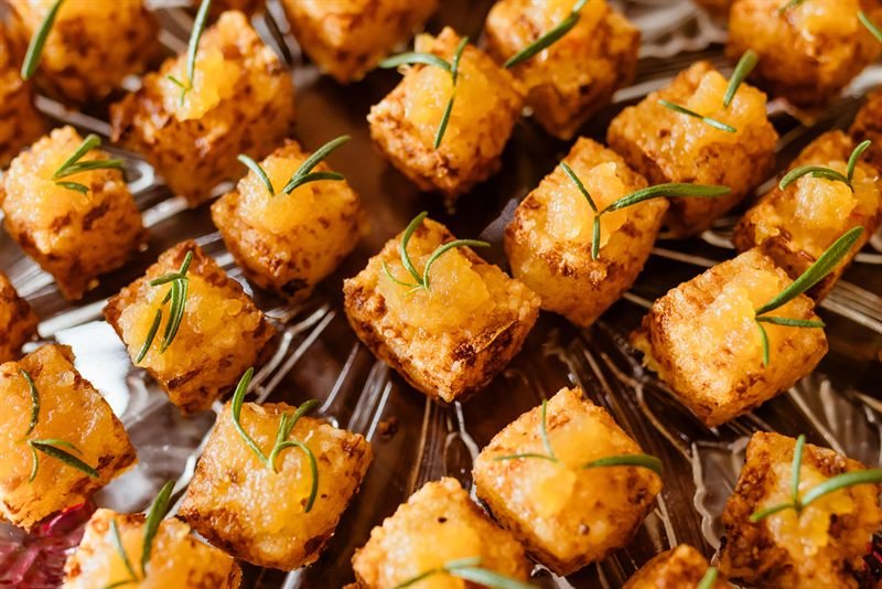 Crisp golden rice squares topped with rosemary on a platter