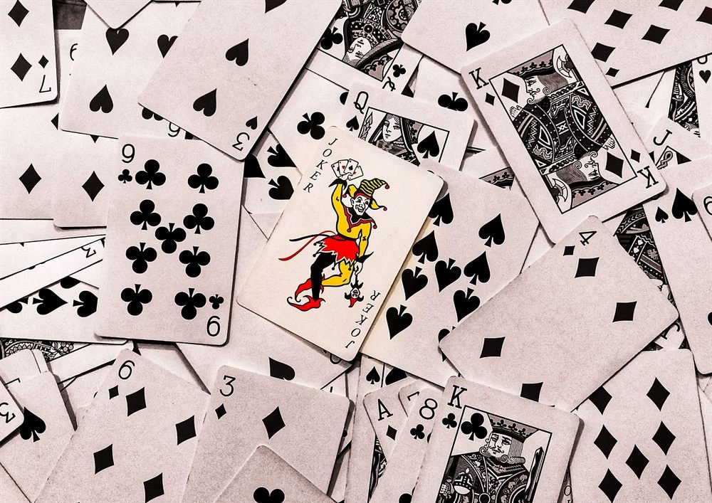 A joker card face-up on a scattered spread of playing cards